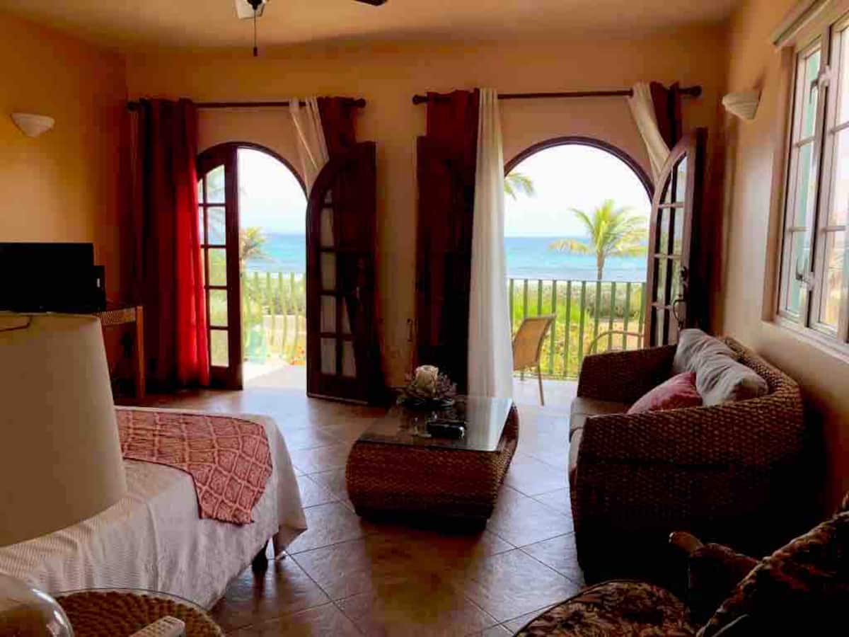 Sea Mist Lower living space opening through dark wooden arches toward palms and the sea